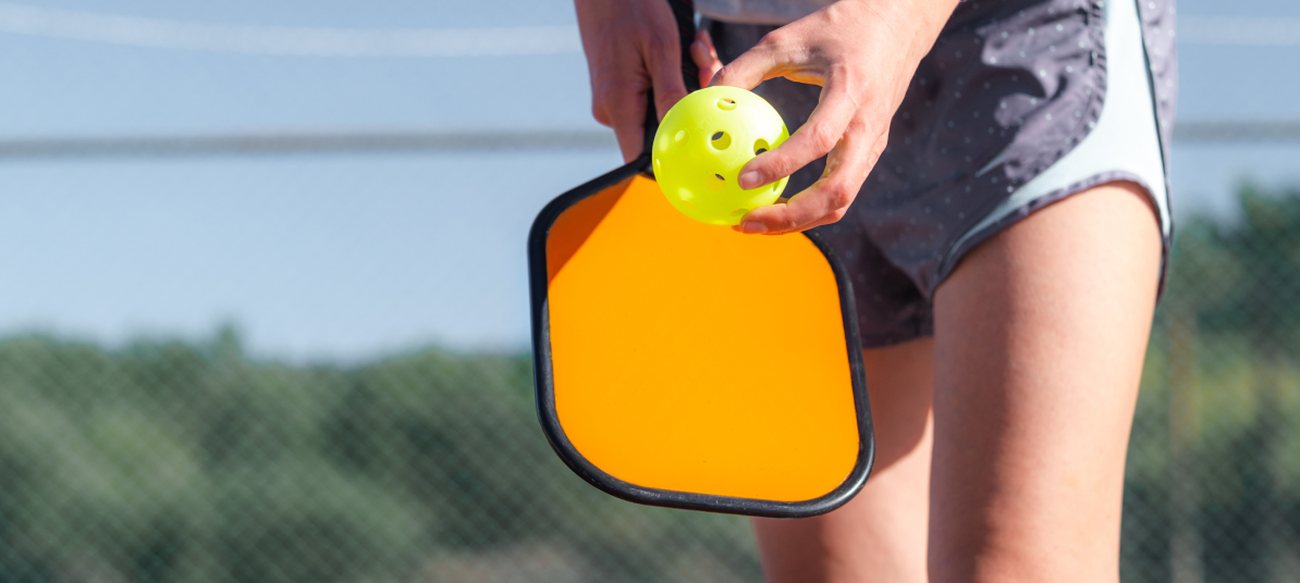 A player holding a pickleball and a paddle